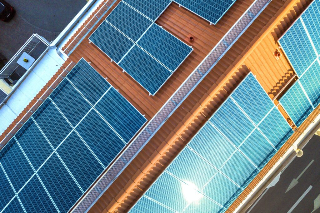 Top view of blue solar photo voltaic panels system on apartment building roof top. Renewable